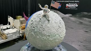 closeup of a spherical cake that looks like the moon, with a spacesuit-wearing astronaut on it