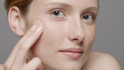 Close up of part of young woman&#039;s face, applying concealer