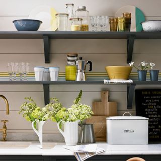 open shelving in white panelled kitchen with vases