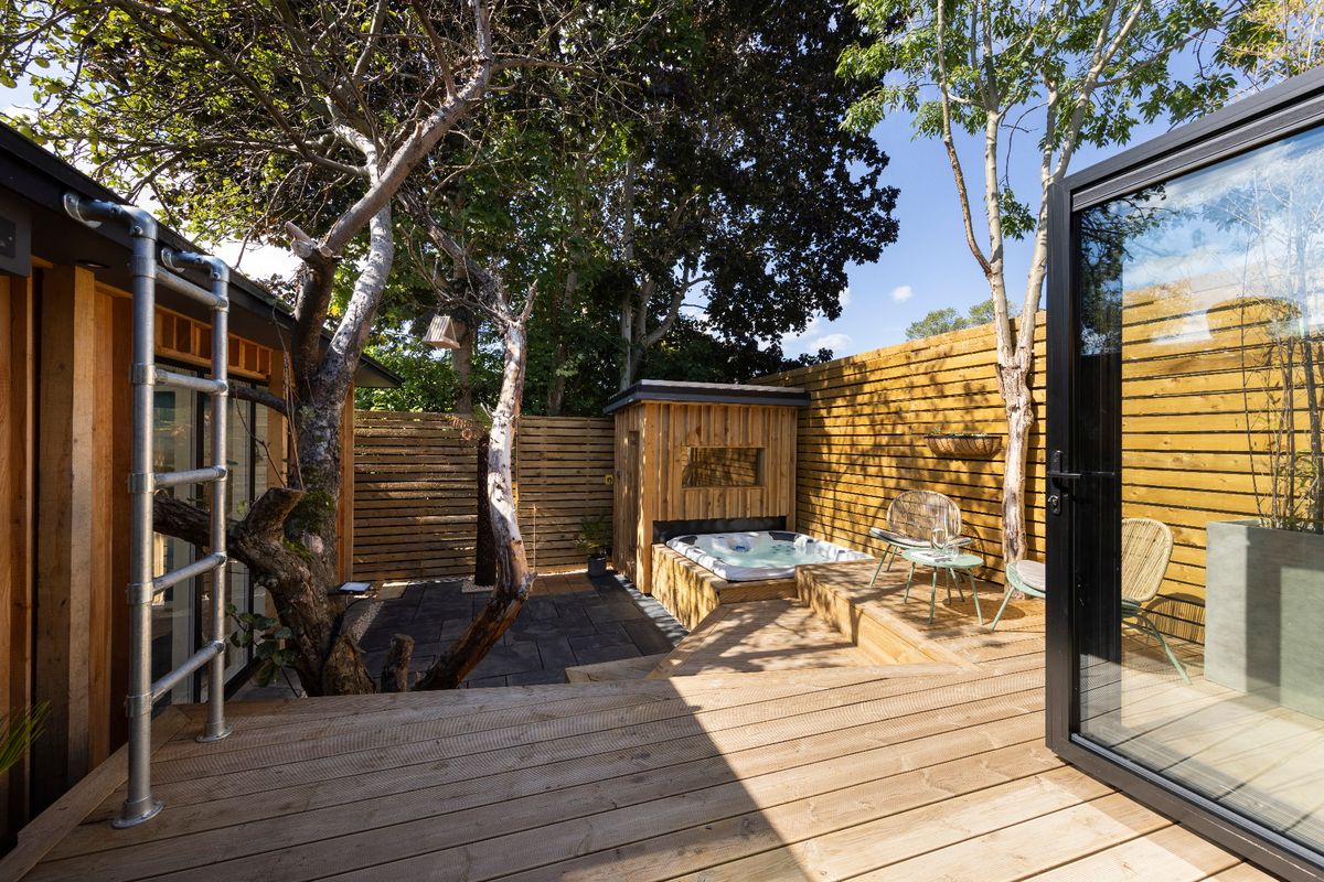 A decking area with a hot tub and a home sauna