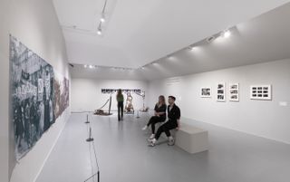 room with images on walls, people looking at art