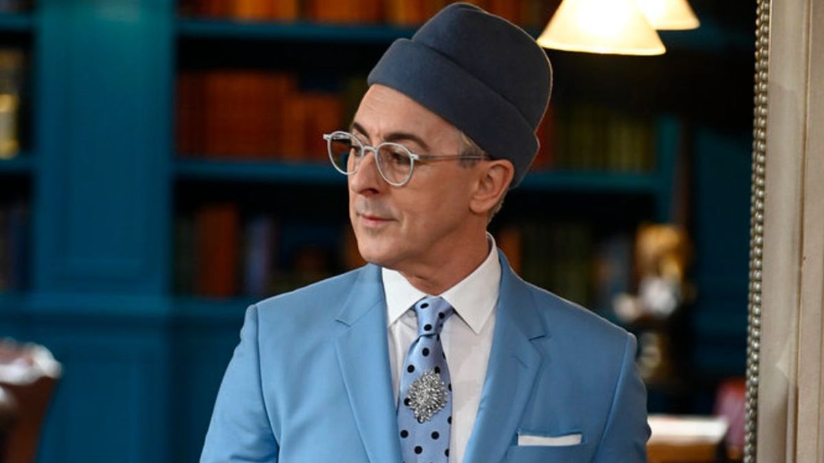 Alan Cumming decked out in a blue suit with a blue brimless hat