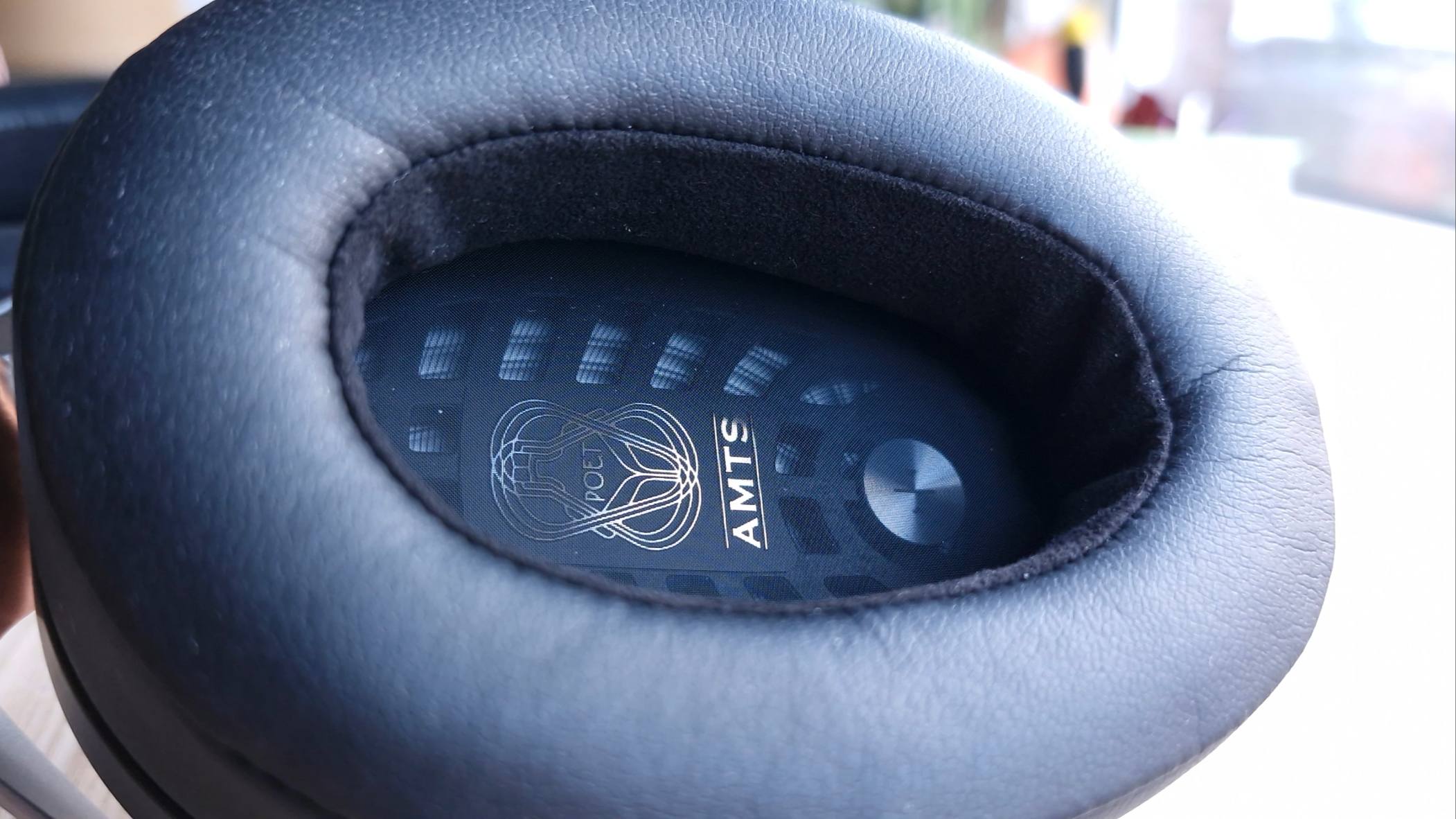 Close up image of earcups of the Meze Audio Poet open-back over-ear headphones, on a wooden table