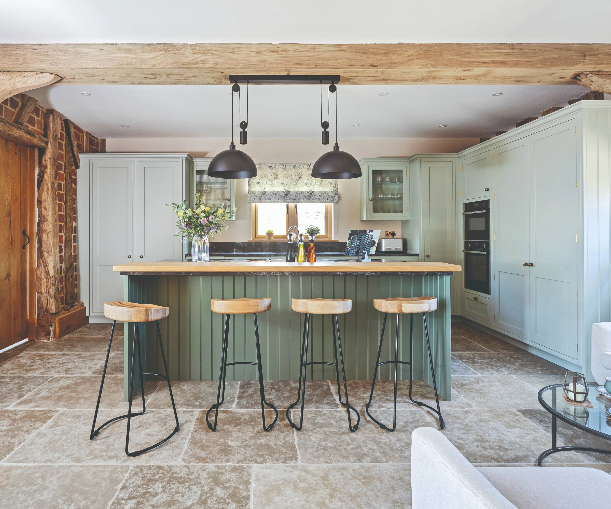 Kitchen area in a barn conversion with industrial pendant lighting hanging over the island bar