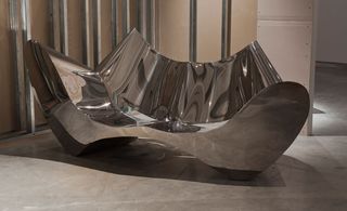 Sofa constructed from reflective, curved metal
