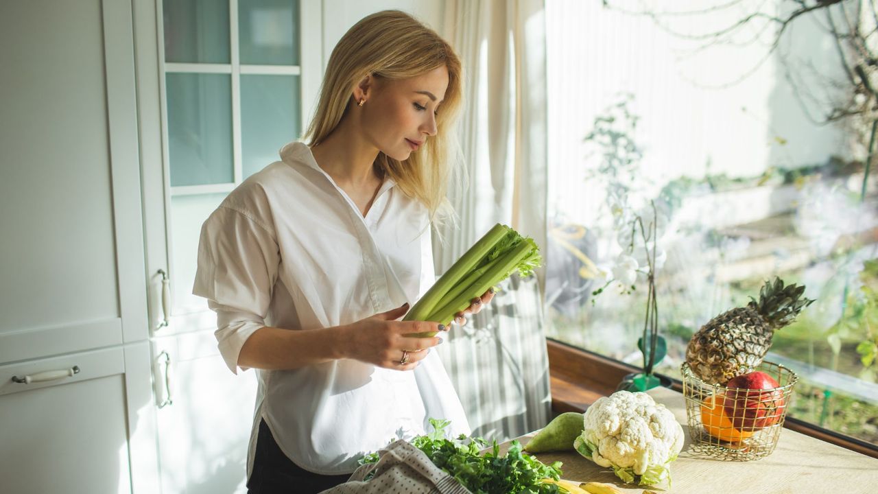 Flat stomach foods: A woman unpacking a healthy food shop at home