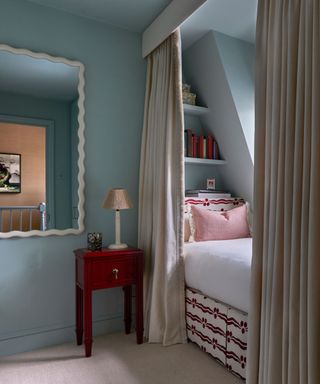 studio duggan blue bedroom with a bed nook and unexpected red bedside table