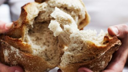 Bread being broken between two hands, representing one of the worst foods to have late at night