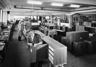 An archive image of a cabinet making / furniture workshop with three craftsman working.