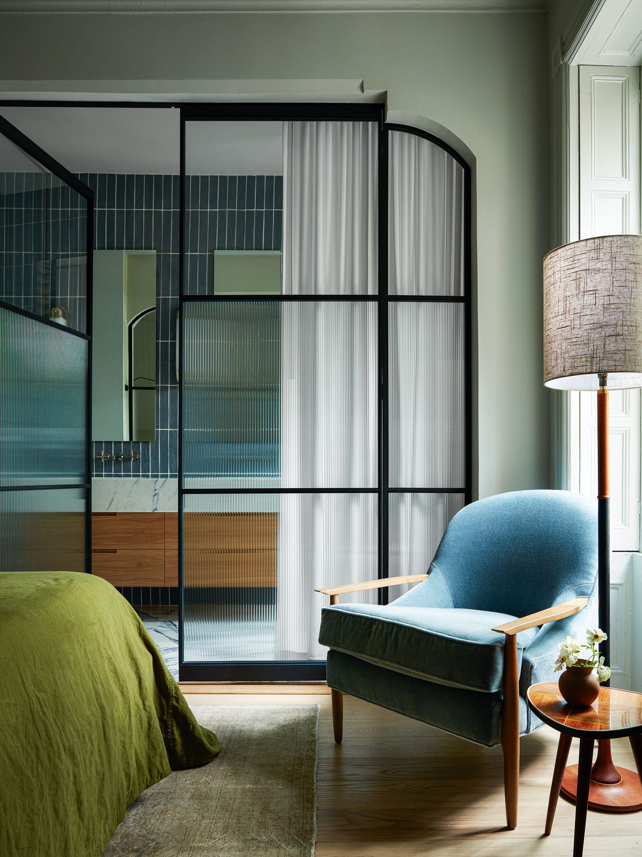 Looking through glass partition doors from the main bedroom to the en suite bathroom