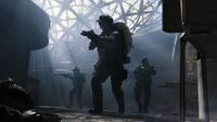 Three soldiers in tactical gear and helmets move through a smoky, industrial indoor space with a large, geometric glass ceiling structure above them.