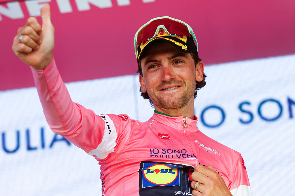 Giulio Ciccone gives a thumbs up in the pink jersey on the podium