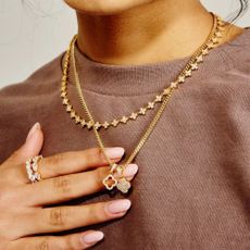 Woman wearing Cernucci gold necklaces and silver ring, with brown jumper