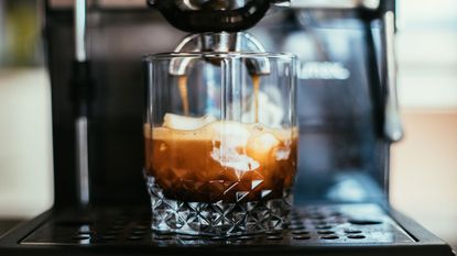 One of the different types of coffee makers, an automatic machine, making a coffee shot over ice cream in a glass