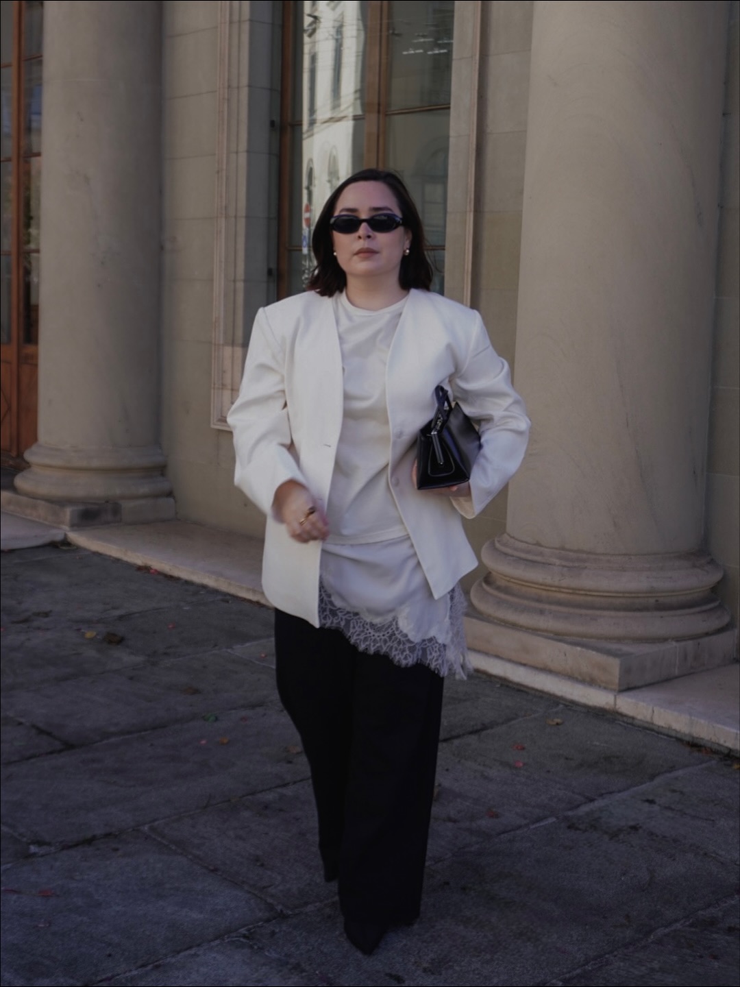 Influencer Indira C. wearing a lace=hem camisole, white blazer and wide-leg trousers.