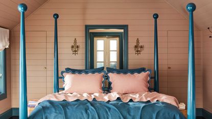 a pink bedroom with blue four poster bed