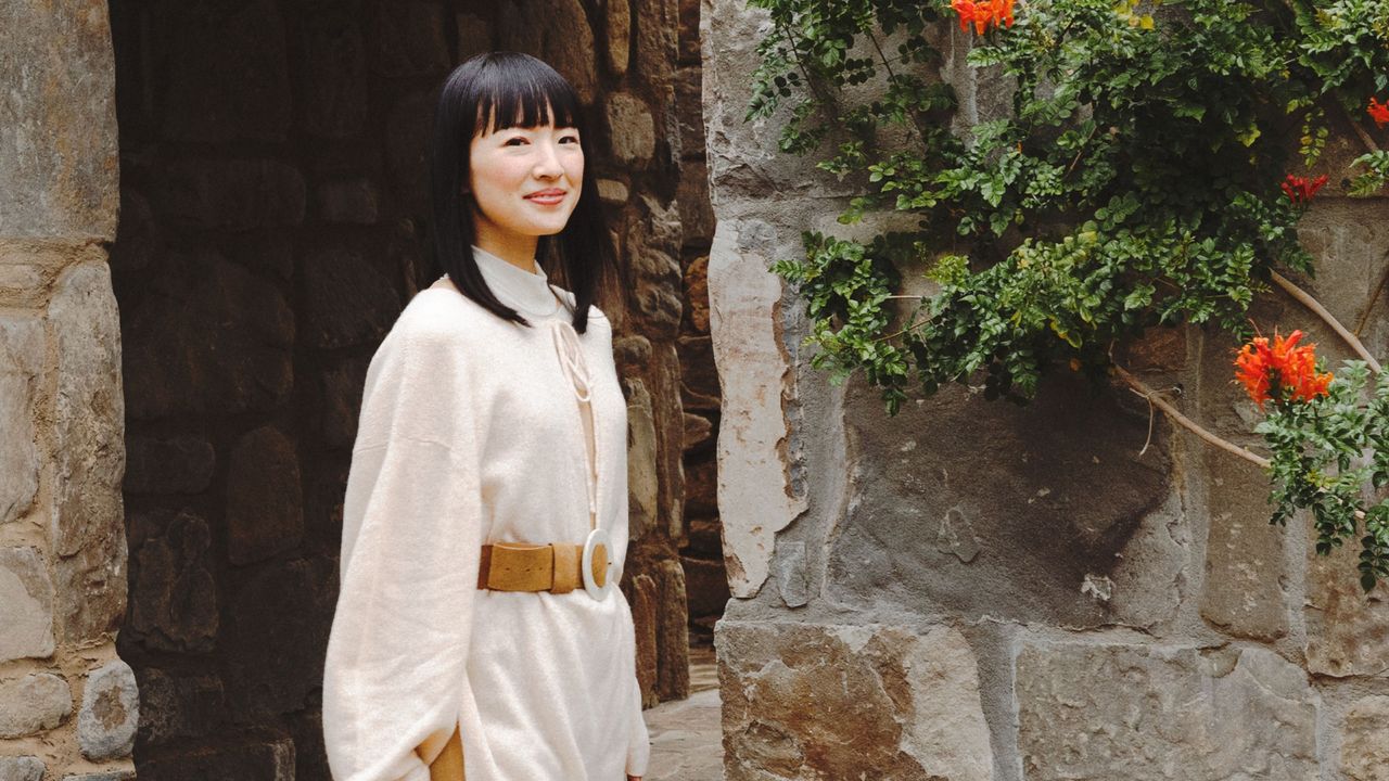 Marie Kondo standing next to stone wall