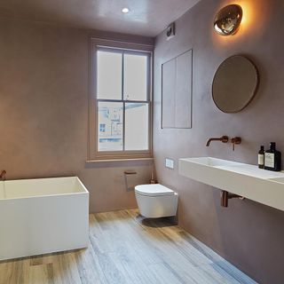 bathroom with wooden flooring and white bathtub