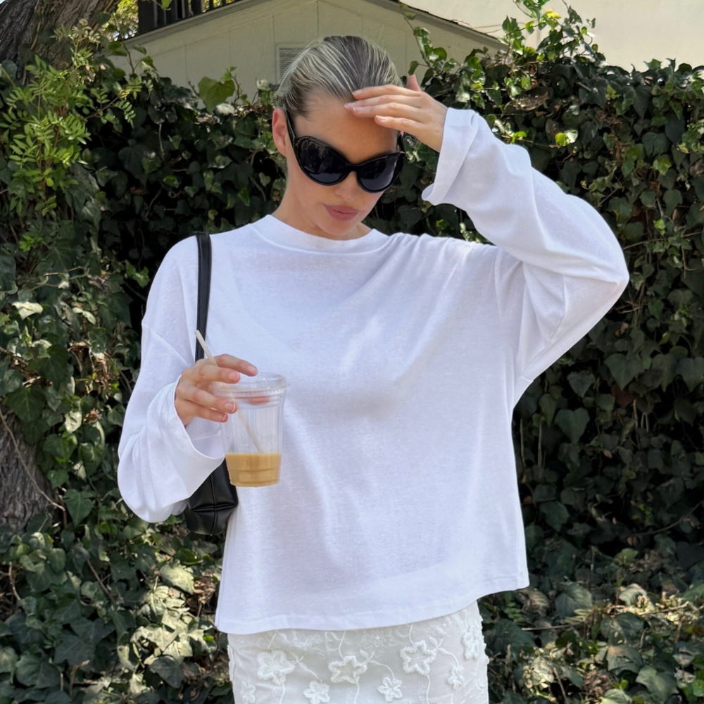 Model @hoskelsa wears a baggy long-sleeve t-shirt with a knee-length skirt and ballet pumps.