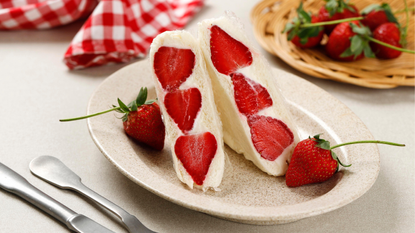 Japanese strawberry sando on a plate next to a bowl of strawberries.