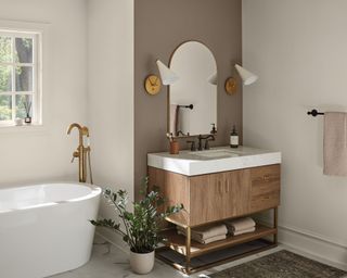 modern bathroom with brown accent wall, white walls, freestanding bath and wooden vanity