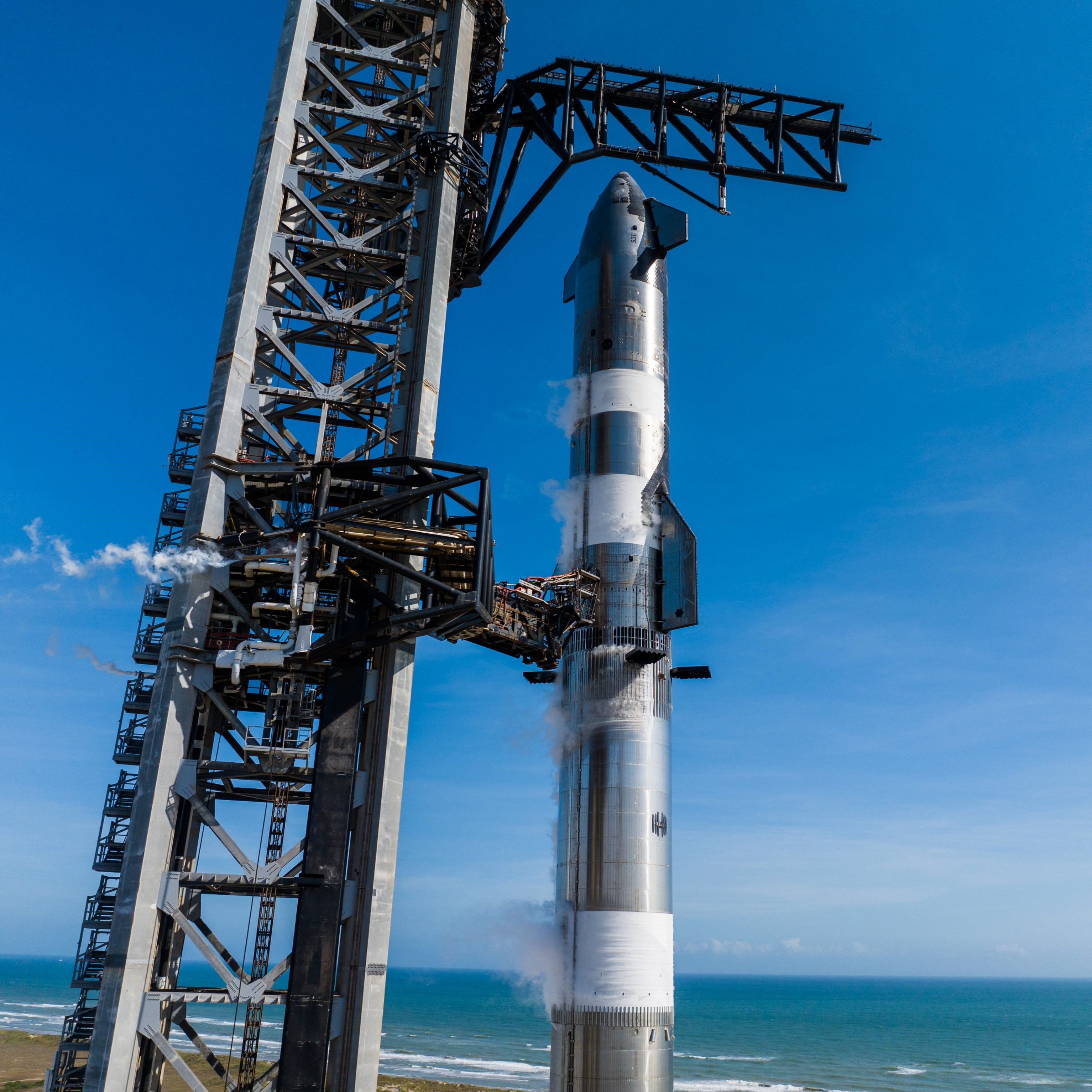 A tall chrome rocket stands next to a black tower, frosted in sections as sections are frosted white from super chilled fuel inside.