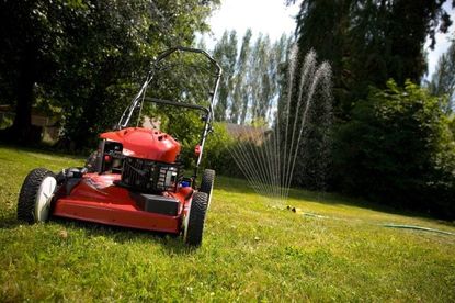Lawn Mower On Lawn With Sprinkler In Background