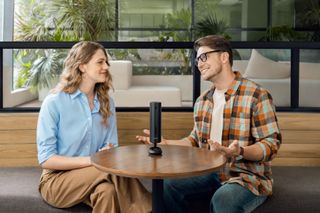 Insta360 Wave device on a table between two people having a casual chat