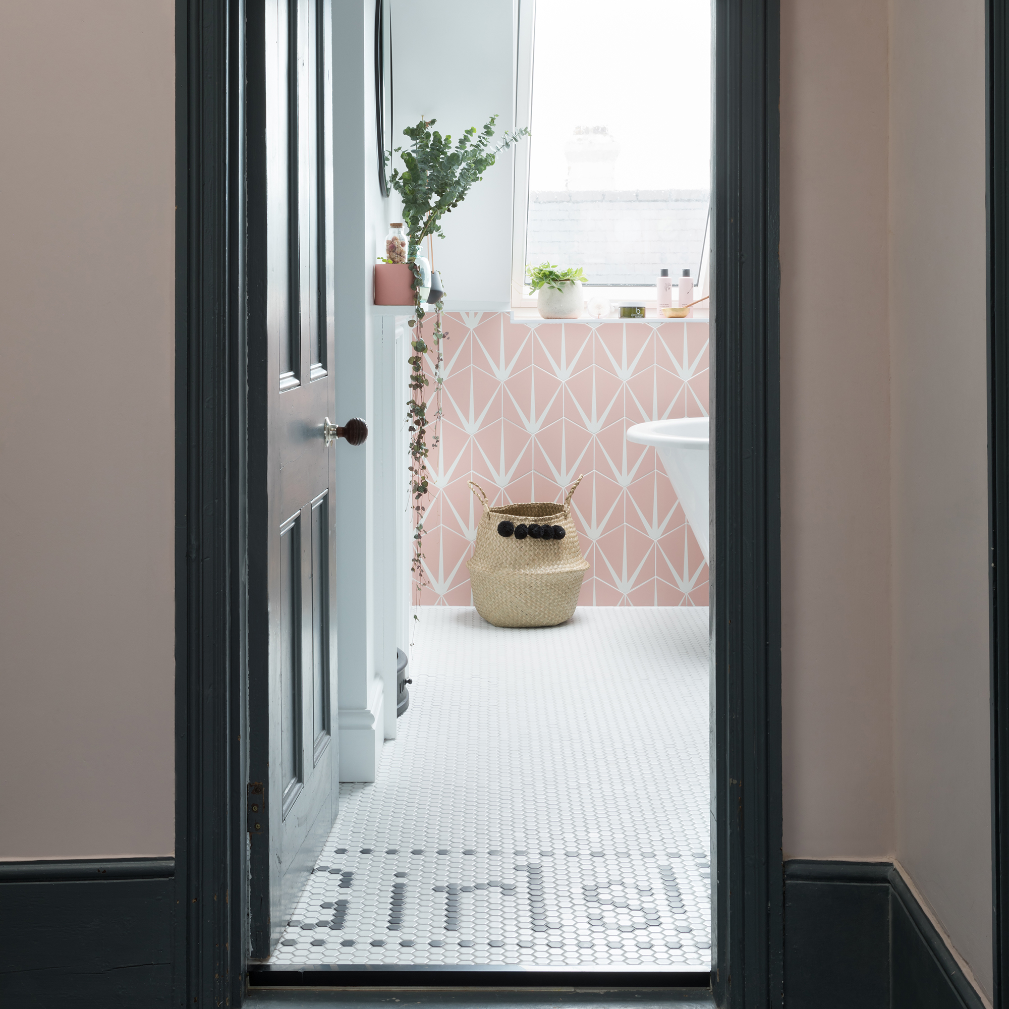 Doorway into a white and pink bathroom with white mosaic tiled floor