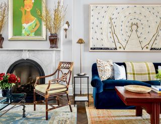Living room with traditional roll-arm blue velvet sofa, selection of antique chairs and side tables, and two contemporary artworks on a white backdrop