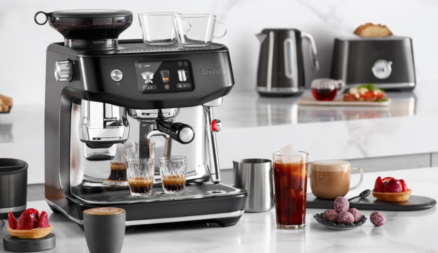 Image of a kitchen with a Breville coffee machine making coffee, various fruit and pastries on the bench and a Breville toaster and kettle behind it