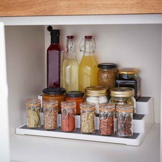 kitchen with white cupboard contains spice bottles and oil