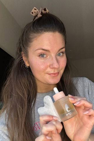 Gua Sha routine - Tori Crowther holding a gua sha tool and a facial oil