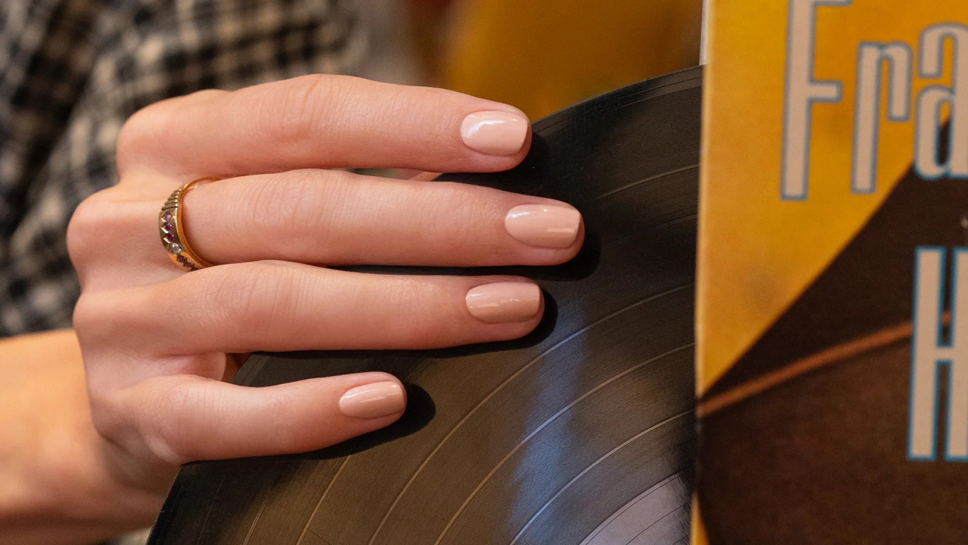 hand with manicure Dune nail polish grabbing a vinyl record