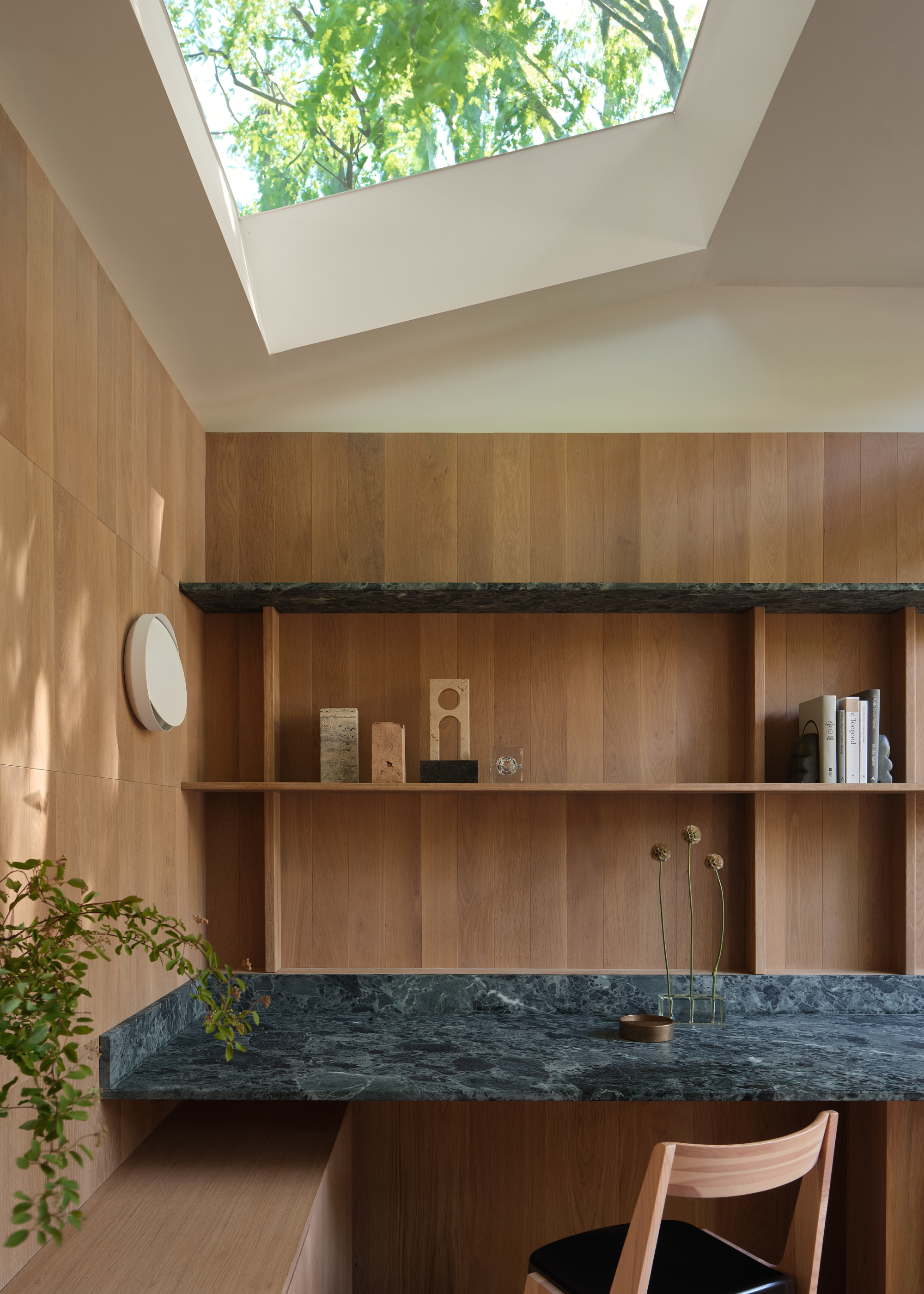 a light filled garden room with a rooflight and oak walls and a green marble desk