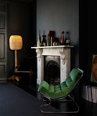 Marble fireplace with black wall decor and green velvet chair