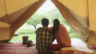 Young couple sitting in tent together.