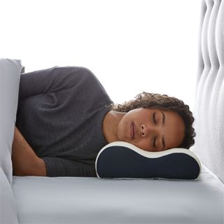 A lifestyle image of a woman resting her head on the Silentnight Sleep Therapy Contour Pillow with her eyes closed.