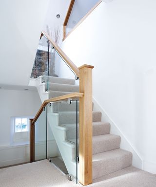 Glass and oak stair railing idea by Neville Johnson with grey carpet and white wall paint decor