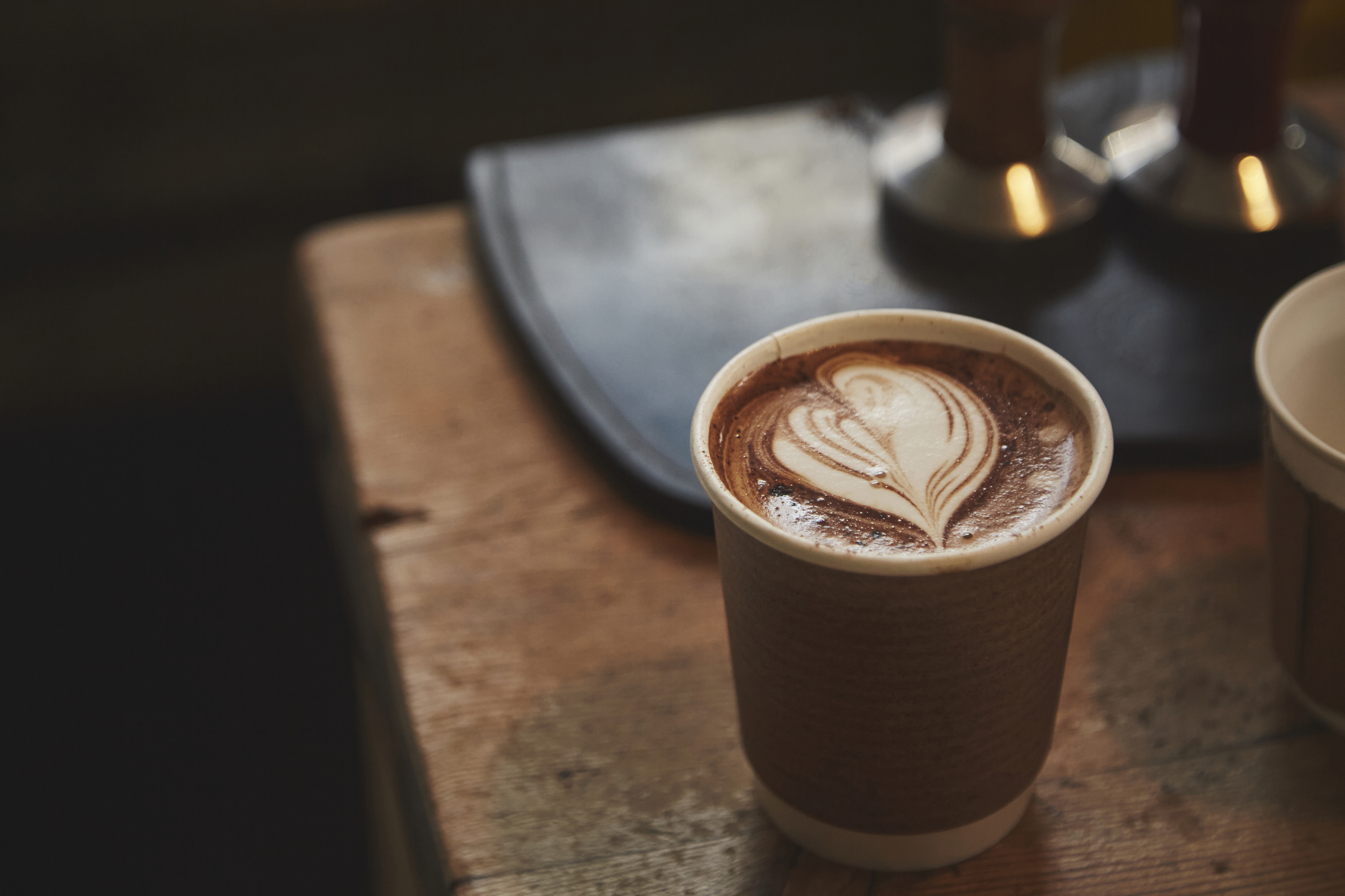 A paper cup filled with hot chocolate and topped with heart foam