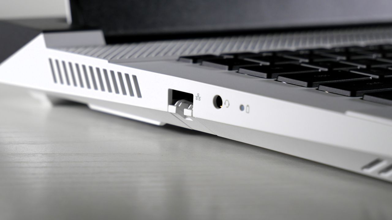Dell G16 (7630) open on a white table, highlighting the ports on the left side, including Ethernet and headphone jack.