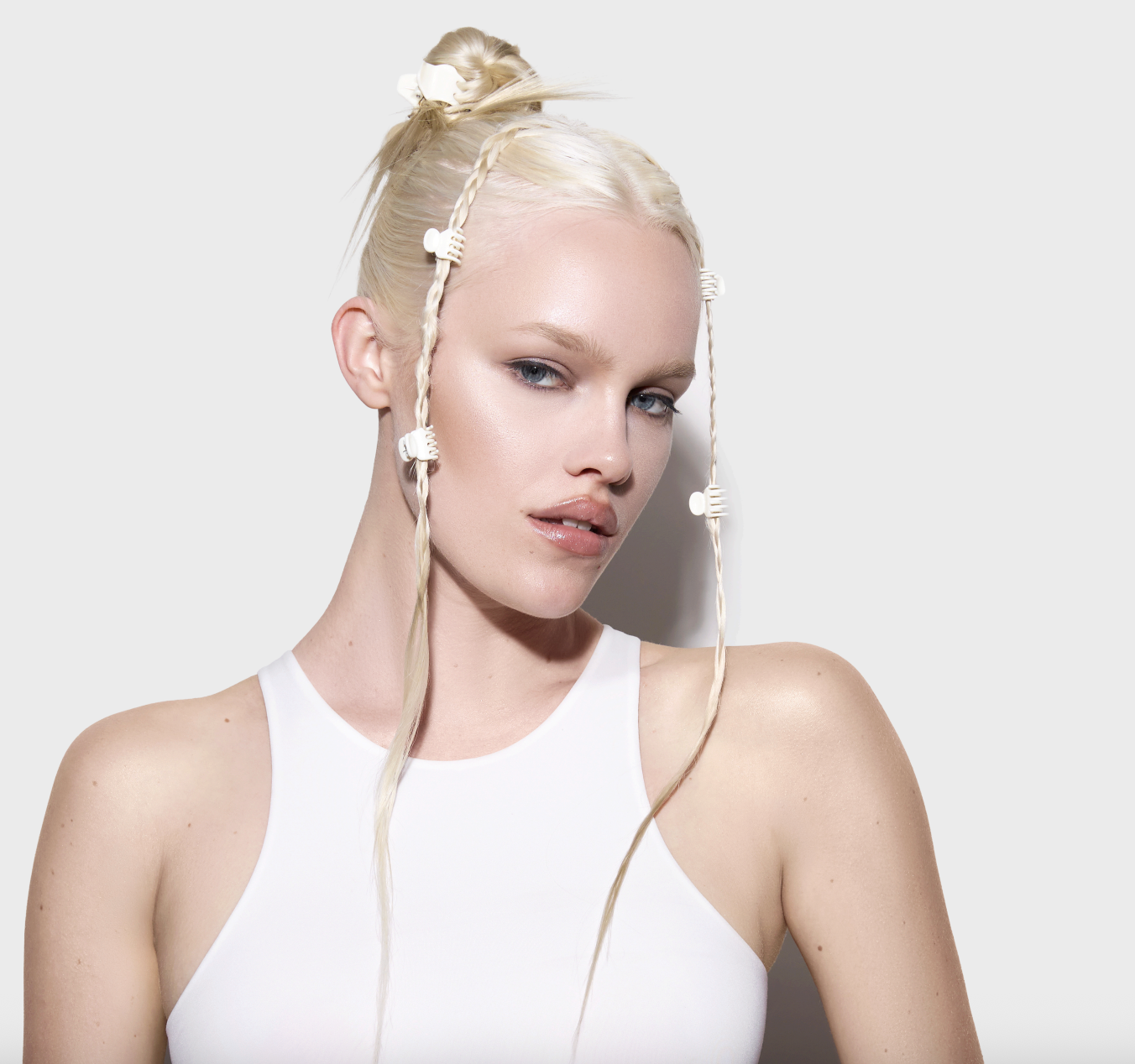 A woman with platinum blond hair wearing small white claw clips throughout her updo hairstyle, which also features baby braids.