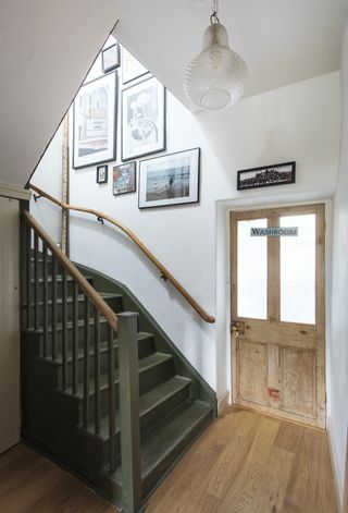 green painted stairs with white walls and gallery wall
