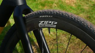 Closeup of Zipp 303 Firecrest wheel on bike with grass behind