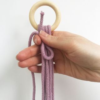 hand holding purple cord in wooden ring