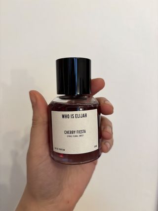 Mica Ricketts holding bottle of Who Is Elijah Cherry Fiesta Eau de Parfum