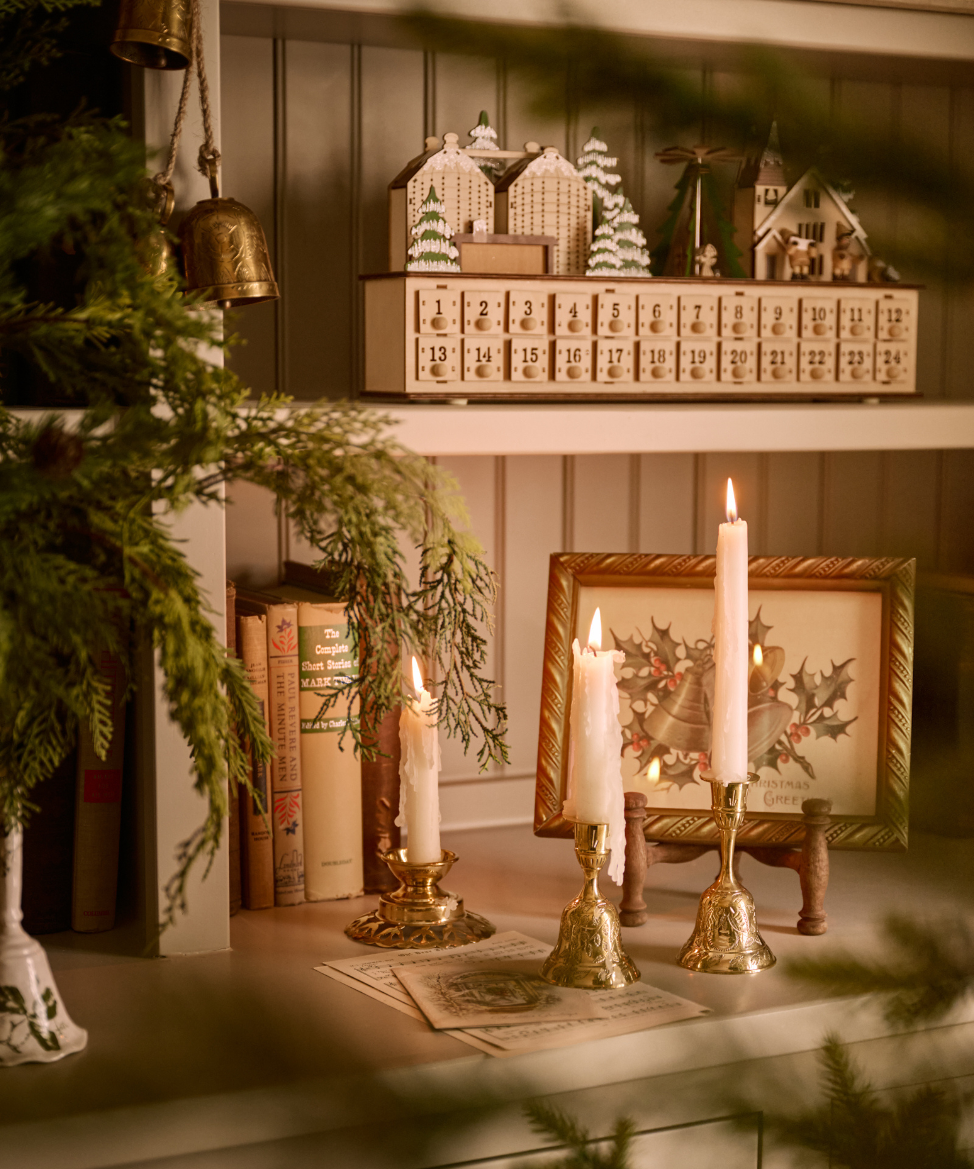 a bookcase with books, candles, an advent calendar, and Christmas decor
