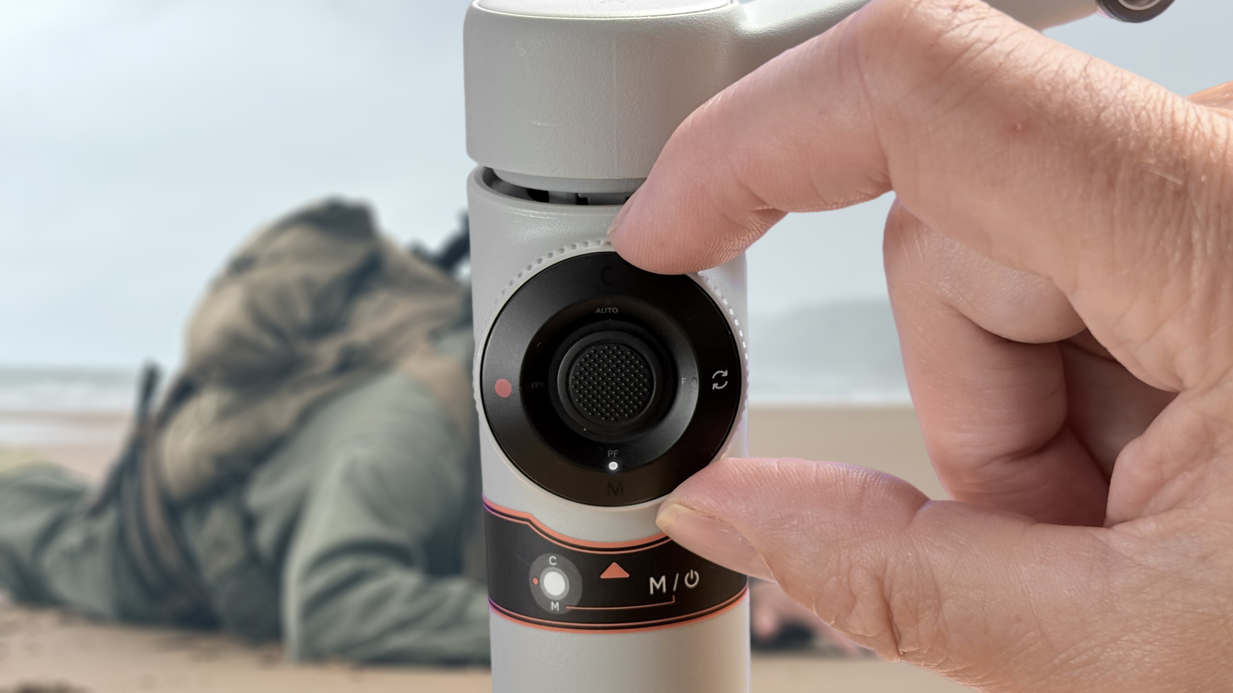 A thumb slides on the back control ring at the rear of the gimbal to adjust camera properties