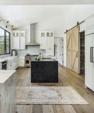 white and oak kitchen with black island and marble tops