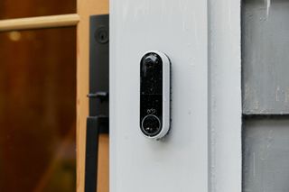 En vit Arlo Video Doorbell sitter monterad utanför en dörr.
